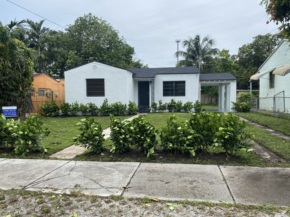 The same Allapattah house after a full gut renovation, refinished in flat white stucco, with the septic tank removed and the house connected to the sewer