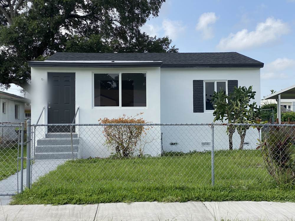 The same Brownsville house after a full gut renovation, refinished in flat white stucco with a new roof