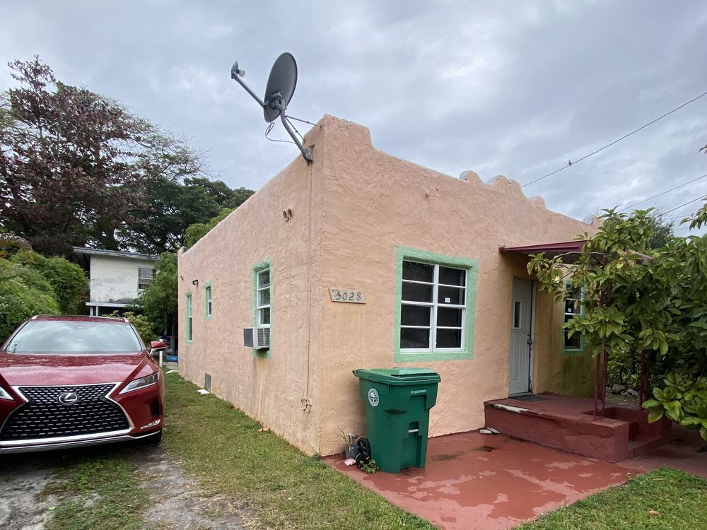 A Buena Vista triplex before renovation, pink stucco with a satellite dish on the parapet